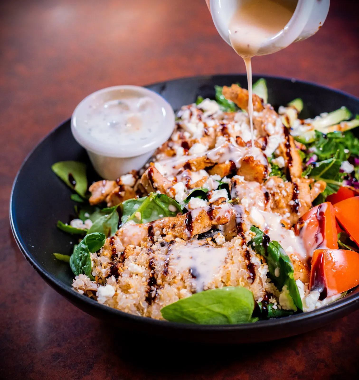 Dressing poured over a Mediterranean salad